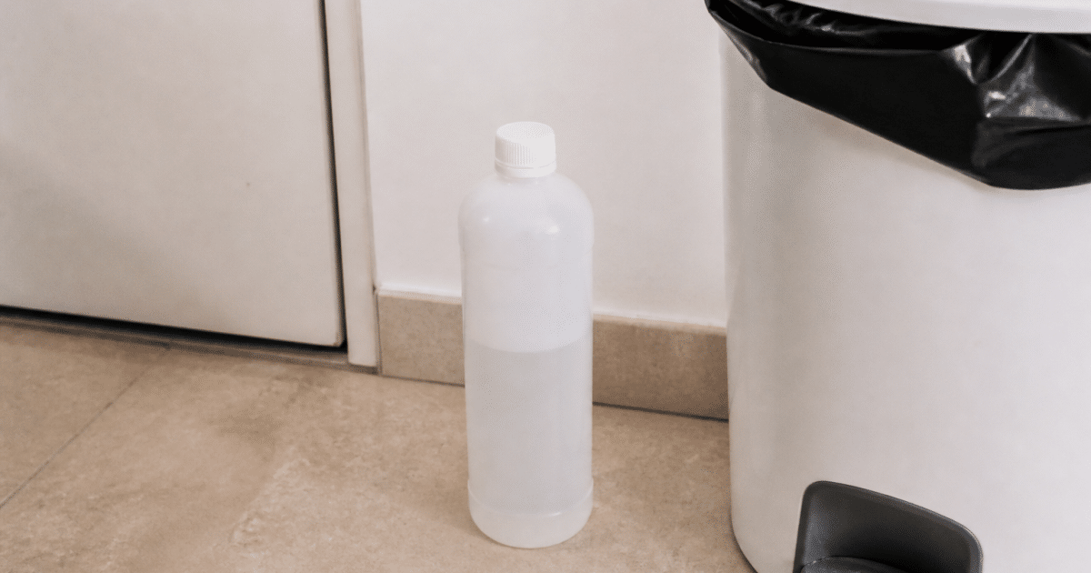 Bouteille plastique acetone posee verticalement pres poubelle recyclage
