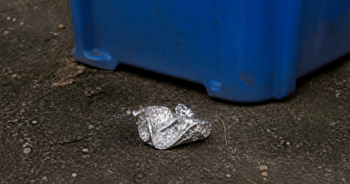 Feuille aluminium froissee posee pres bac recyclage bleu