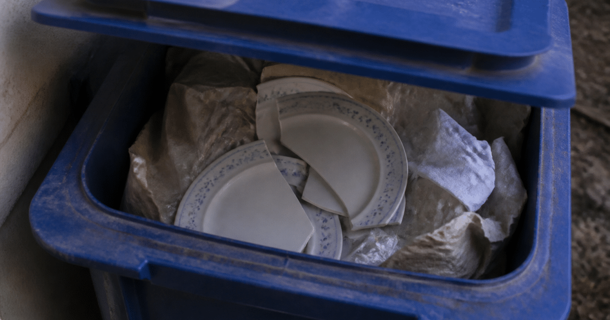 Assiettes cassees posees dans bac recyclage bleu ouvert
