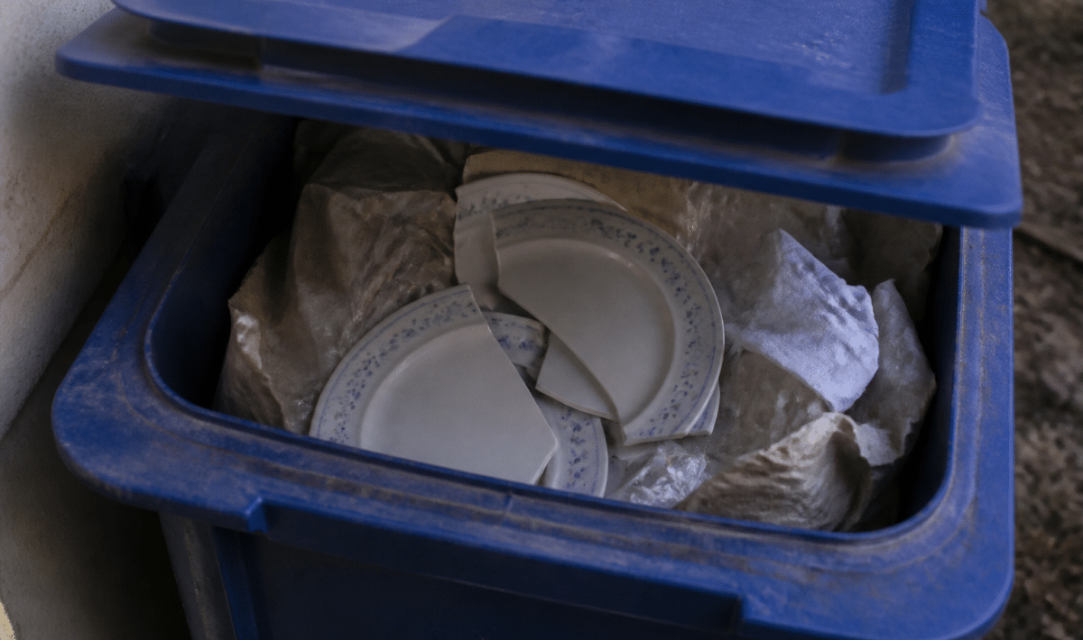 Assiettes cassees posees dans bac recyclage bleu ouvert
