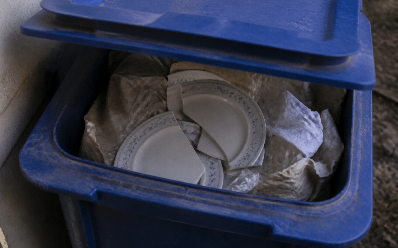 Assiettes cassees posees dans bac recyclage bleu ouvert