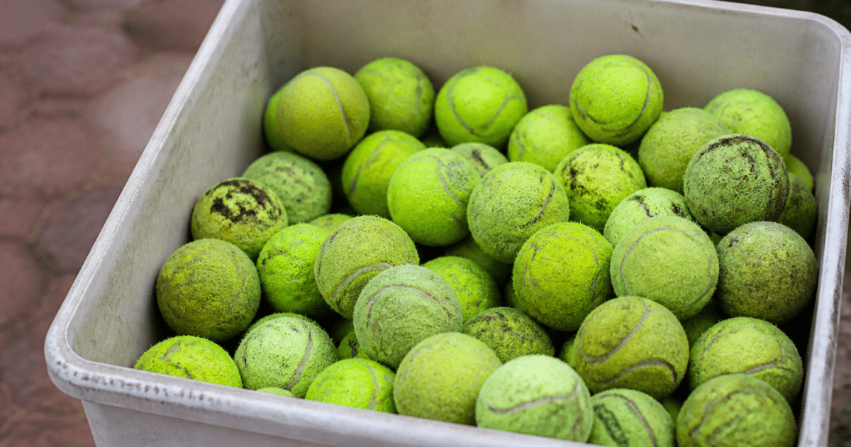 Balles de tennis jaunes usagees empilees dans un bac de collecte