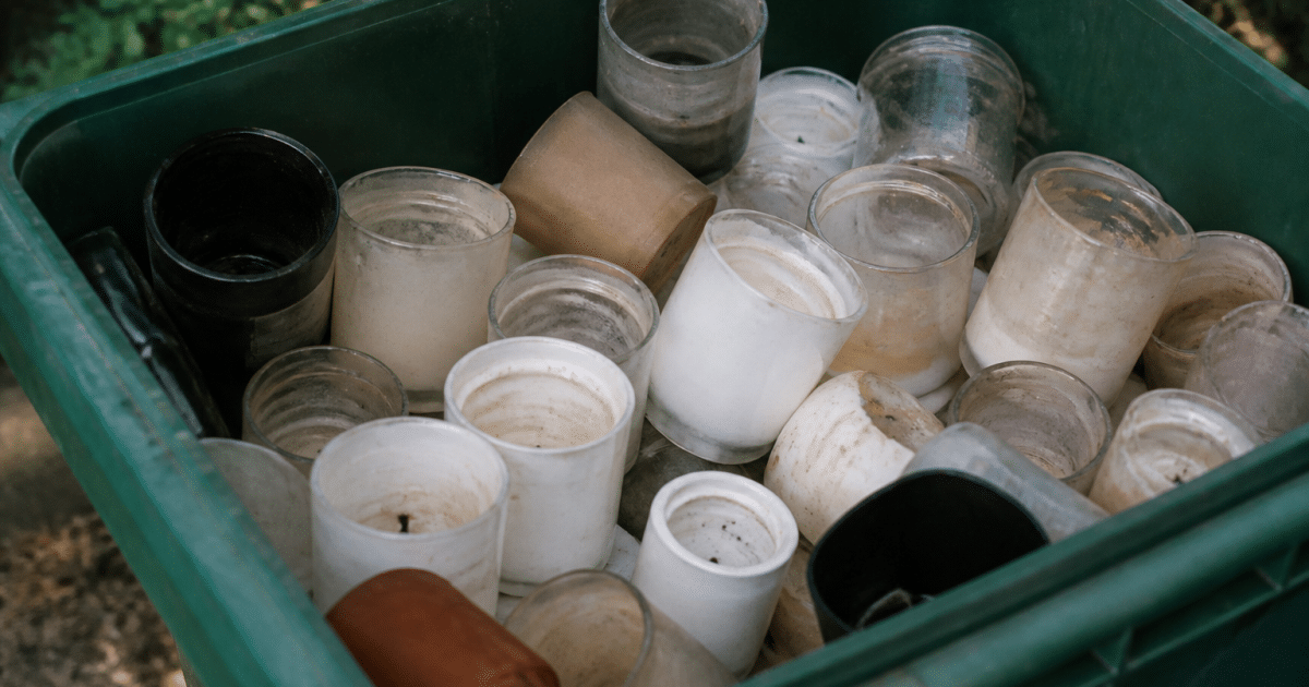 Bougies vides empilees dans bac de recyclage ouvert