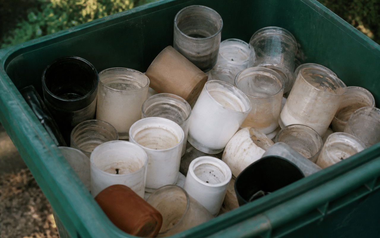 Bougies vides empilees dans bac de recyclage ouvert