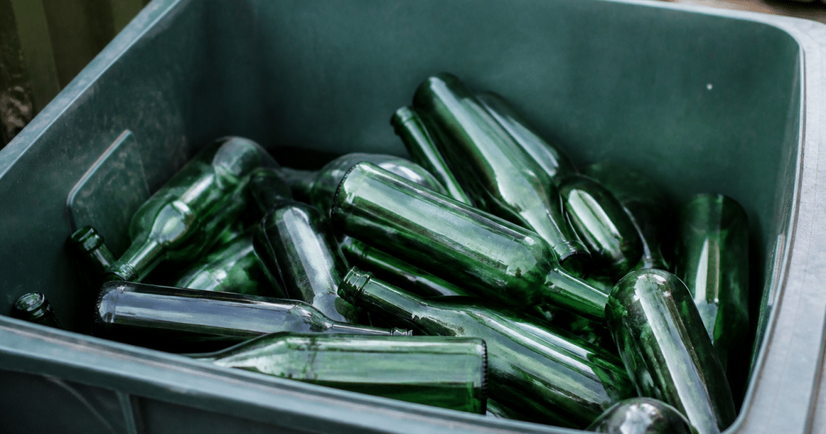 Bouteilles vertes empilees dans bac de tri selectif