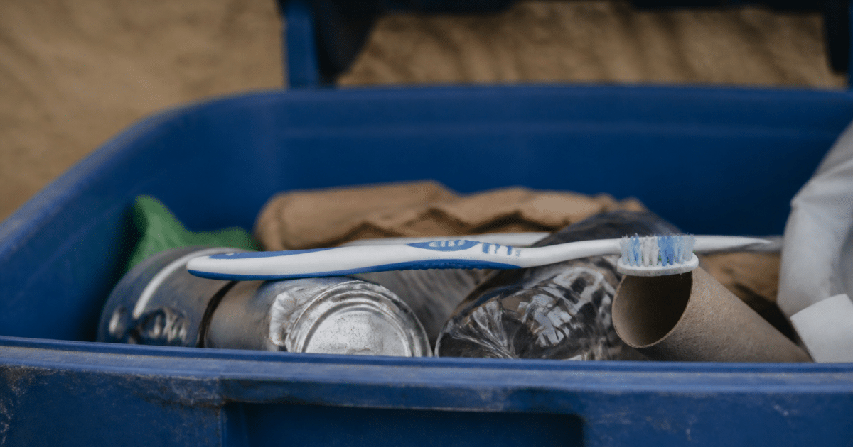 Vieille brosse à dents posée horizontalement dans bac recyclage