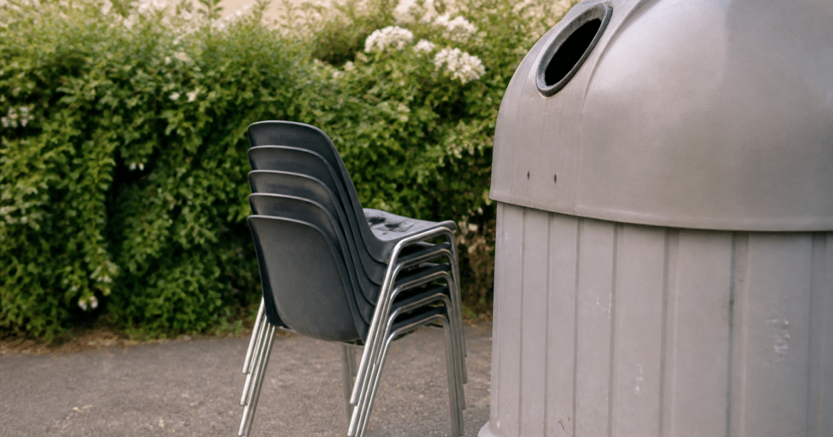 Plusieurs chaises empilees pres d'une benne de recyclage