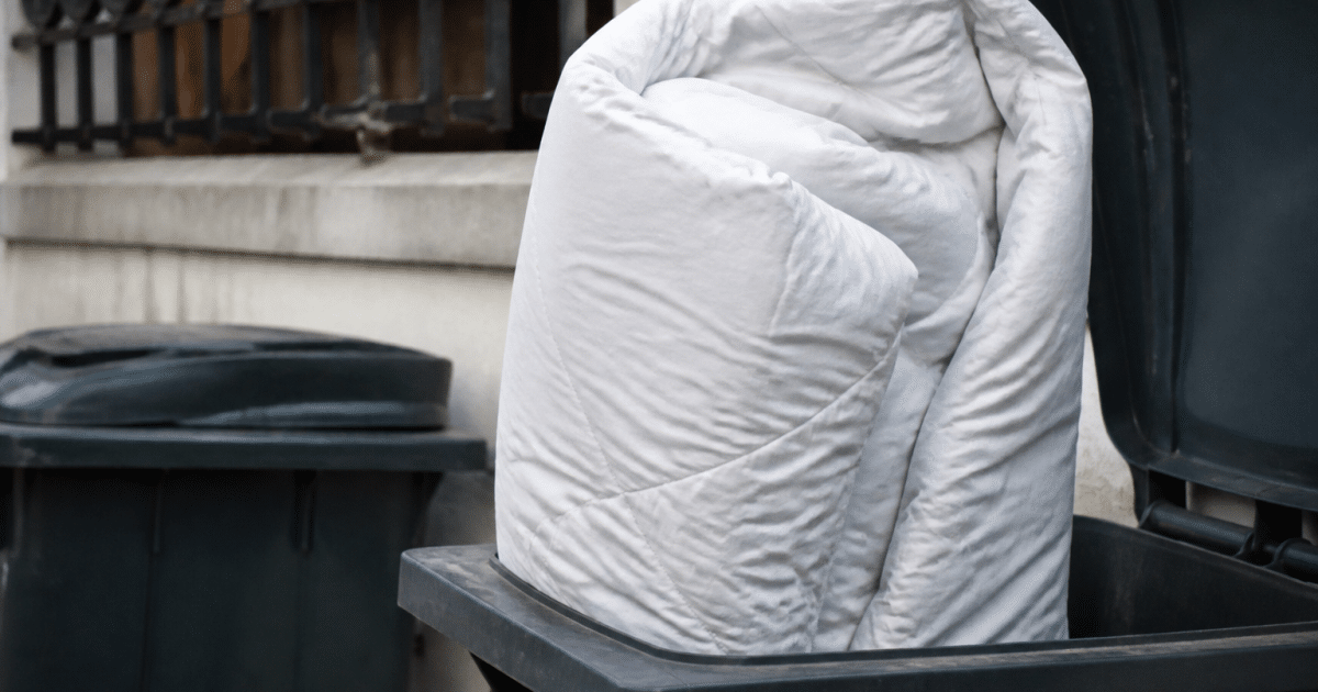 Couette volumineuse posee verticalement dans bac recyclage ouvert