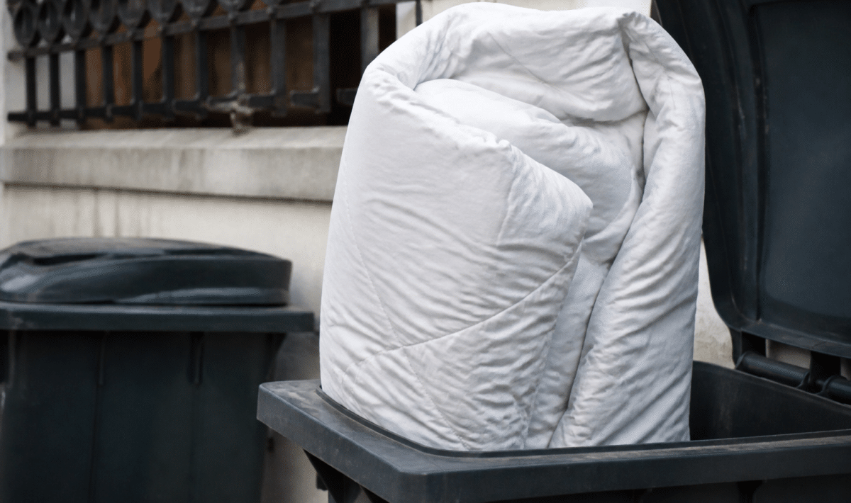 Couette volumineuse posee verticalement dans bac recyclage ouvert