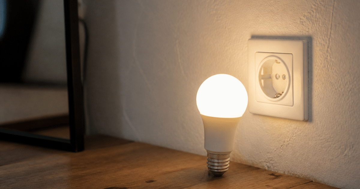 Ampoule LED brillante allumee pres d'une prise electrique murale