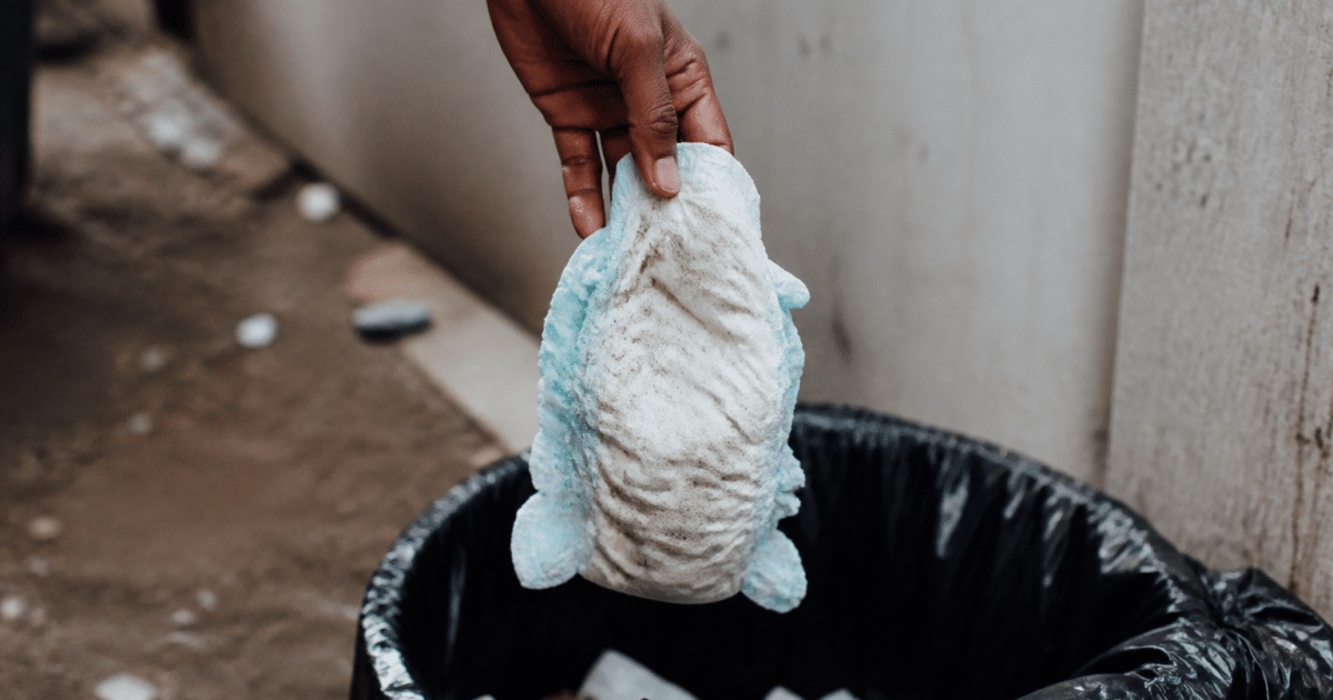 Main tenant couche usagee au-dessus poubelle ouverte