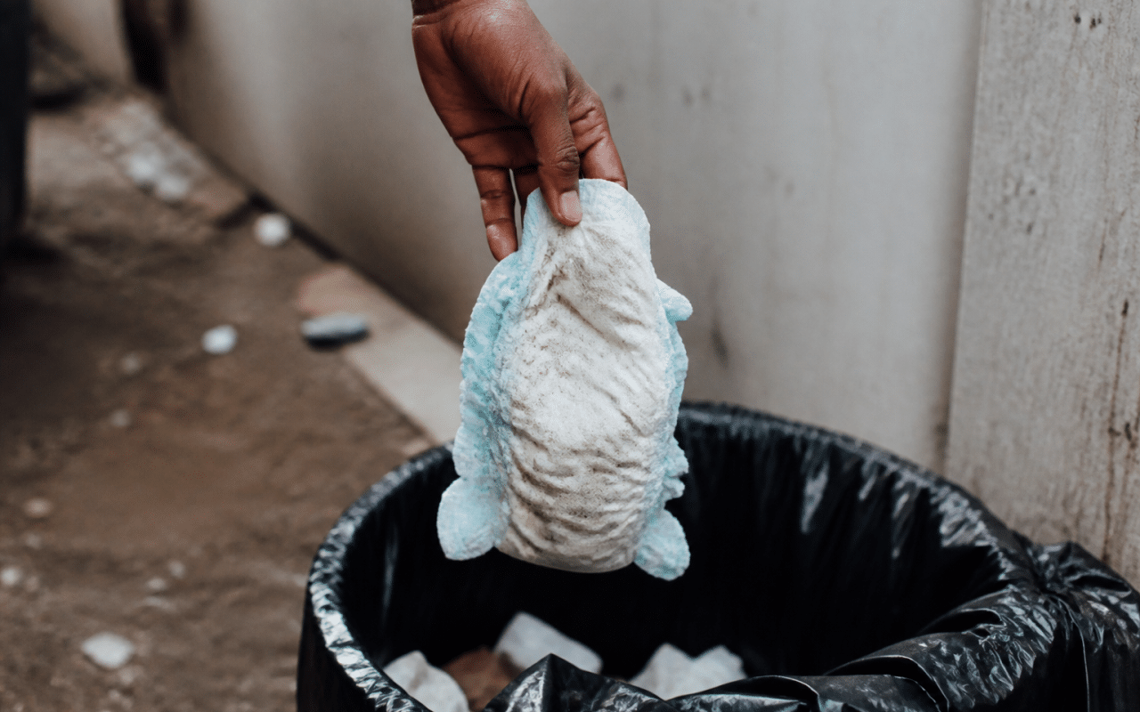 Main tenant couche usagee au-dessus poubelle ouverte