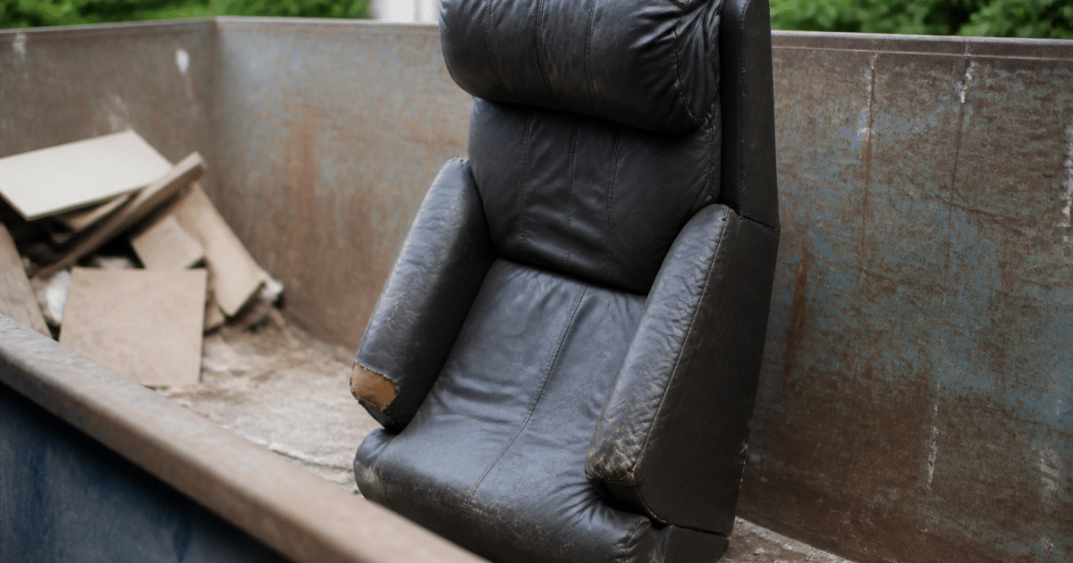 Fauteuil usé posé debout dans benne recyclage extérieur