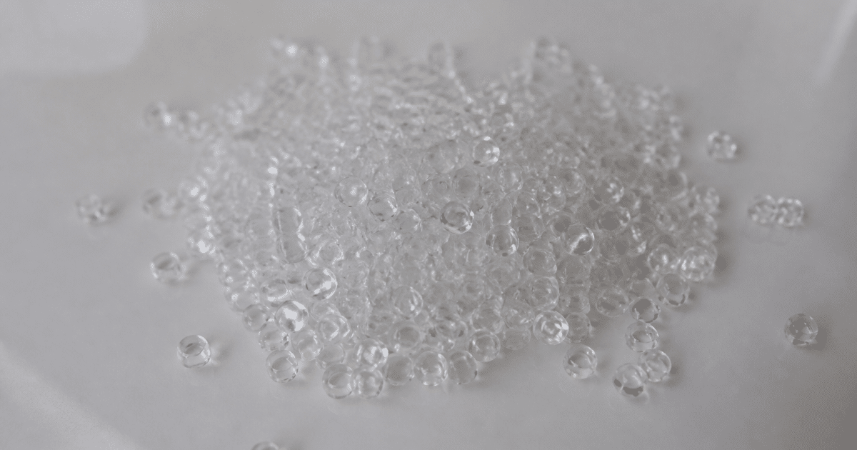 Granules de plastique transparent empilees sur surface lisse blanche