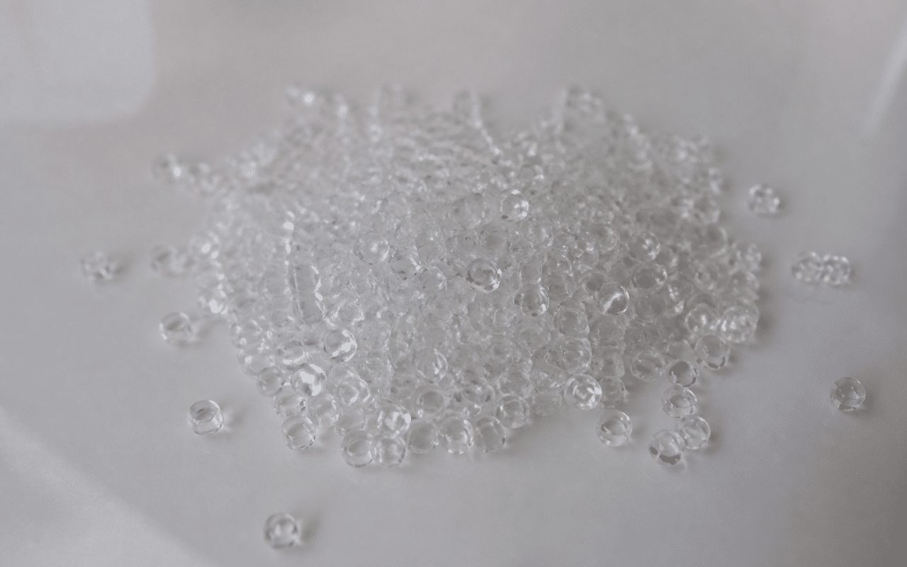 Granules de plastique transparent empilees sur surface lisse blanche