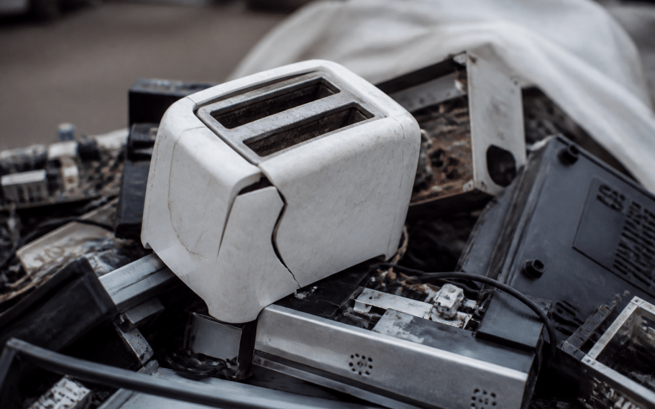Grille-pain brisé posé sur tas de déchets électroniques