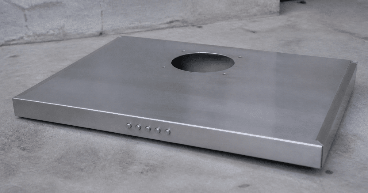 Hotte aspirante metallique posee horizontalement sur sol beton gris