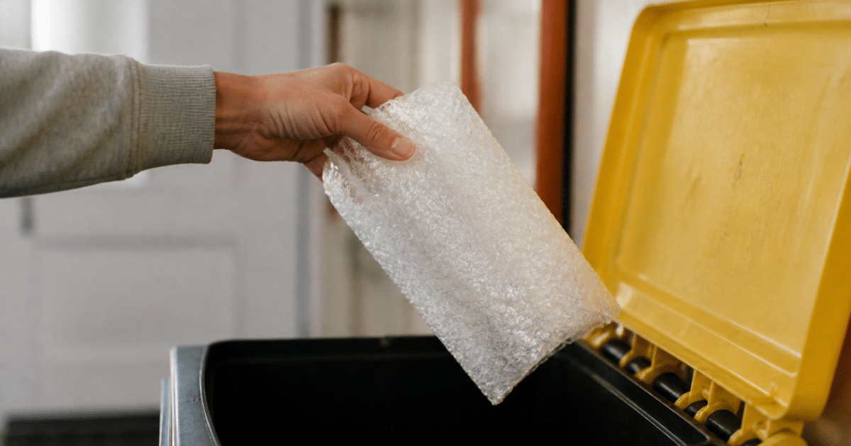 Main tenant rouleau papier bulle au-dessus bac recyclage ouvert