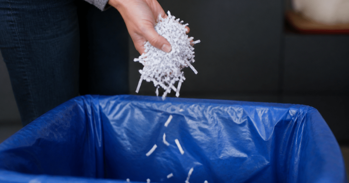Papier dechiquete tombe dans une poubelle de recyclage ouverte