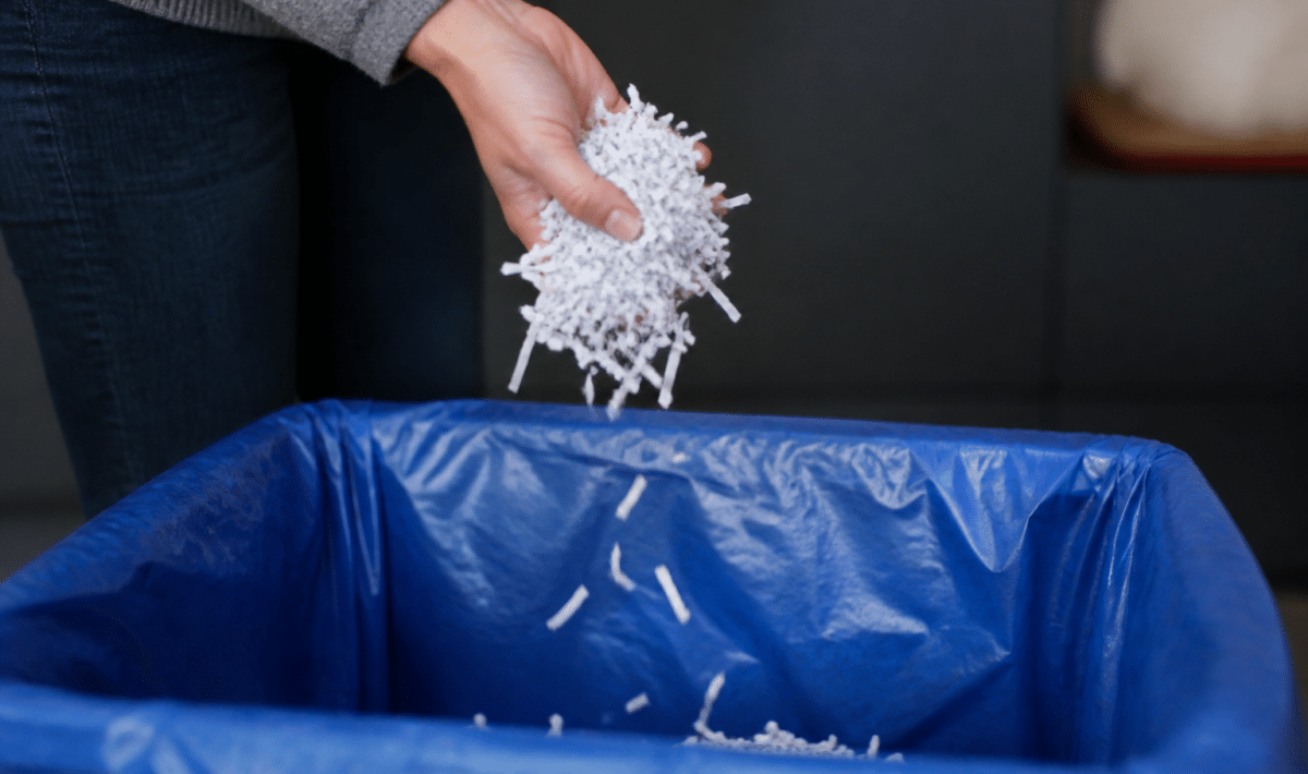 Papier dechiquete tombe dans une poubelle de recyclage ouverte