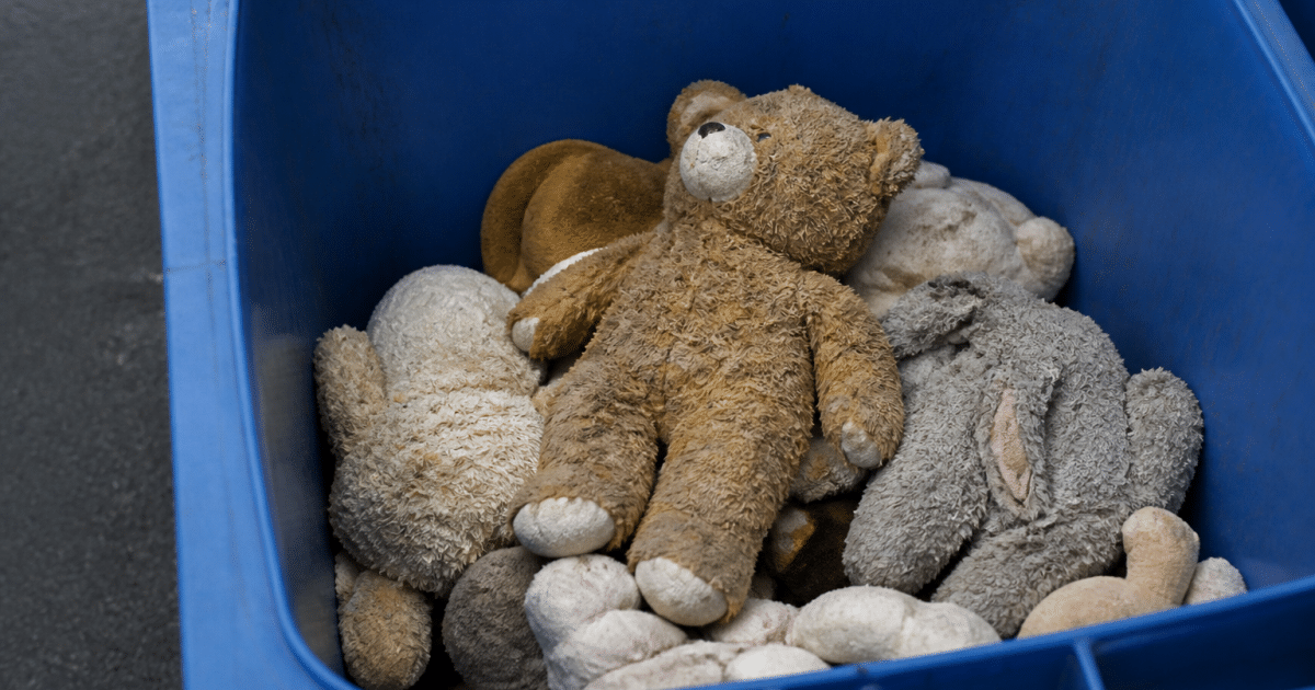 Main versant des peluches usees dans une poubelle de recyclage