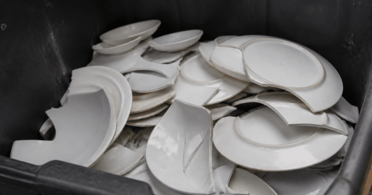 Assiettes cassees blanches empilees dans bac recyclage