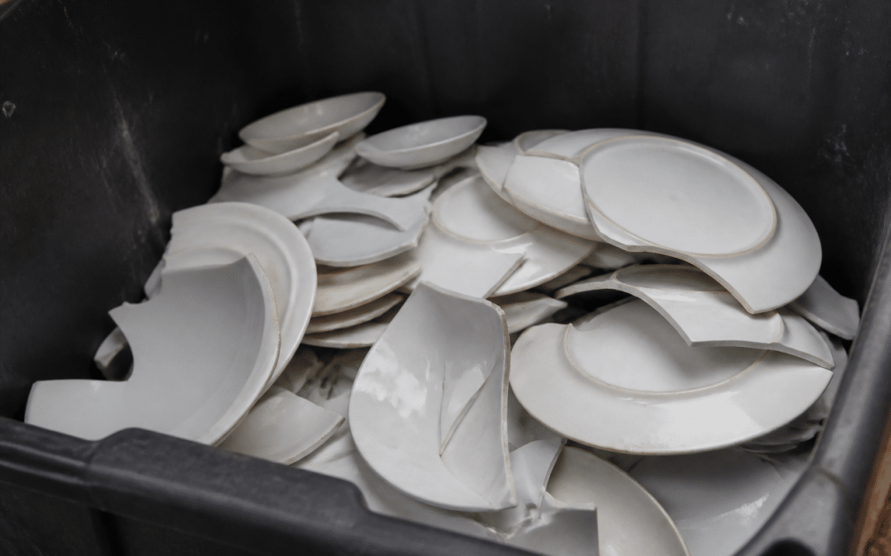 Assiettes cassees blanches empilees dans bac recyclage