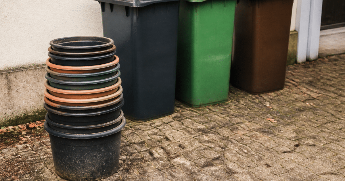 Pots plastique empiles pres de trois bacs de tri selectif