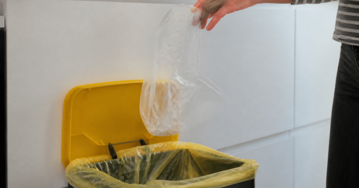 Main tenant sac plastique au-dessus bac recyclage ouvert