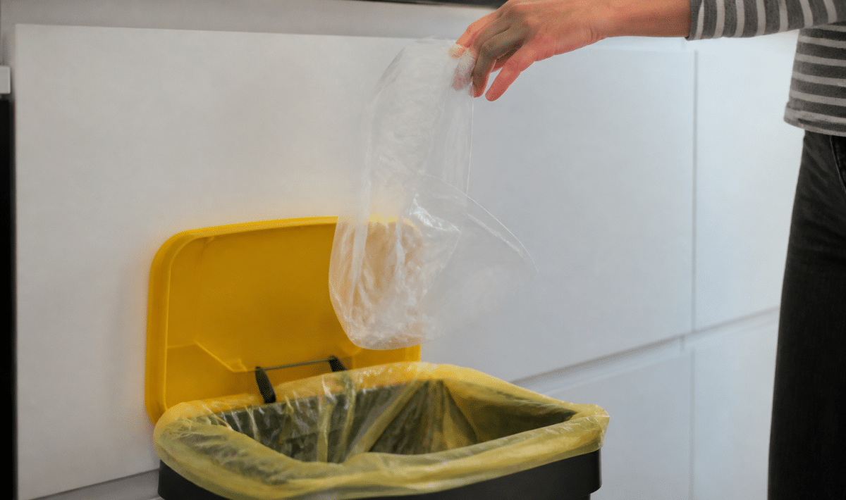 Main tenant sac plastique au-dessus bac recyclage ouvert