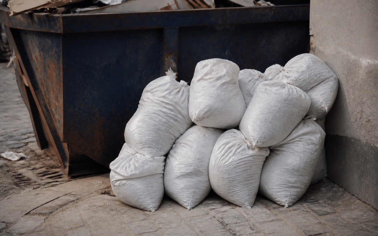 Sacs de plâtre empilés près d'une benne à déchets