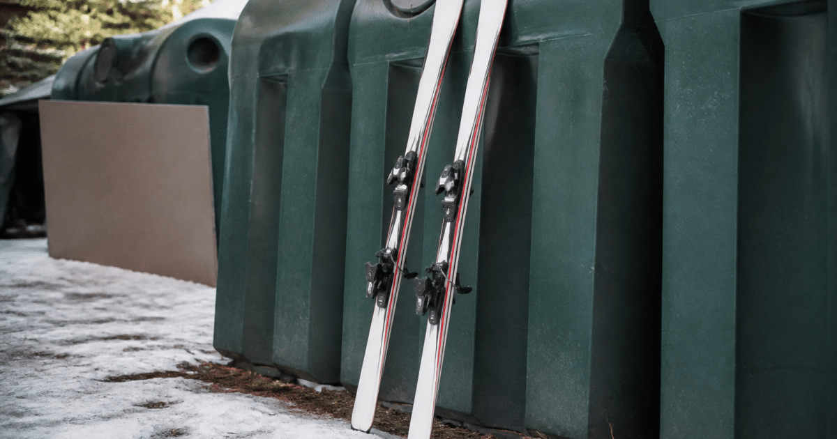 Paires de skis posees verticalement contre benne de recyclage