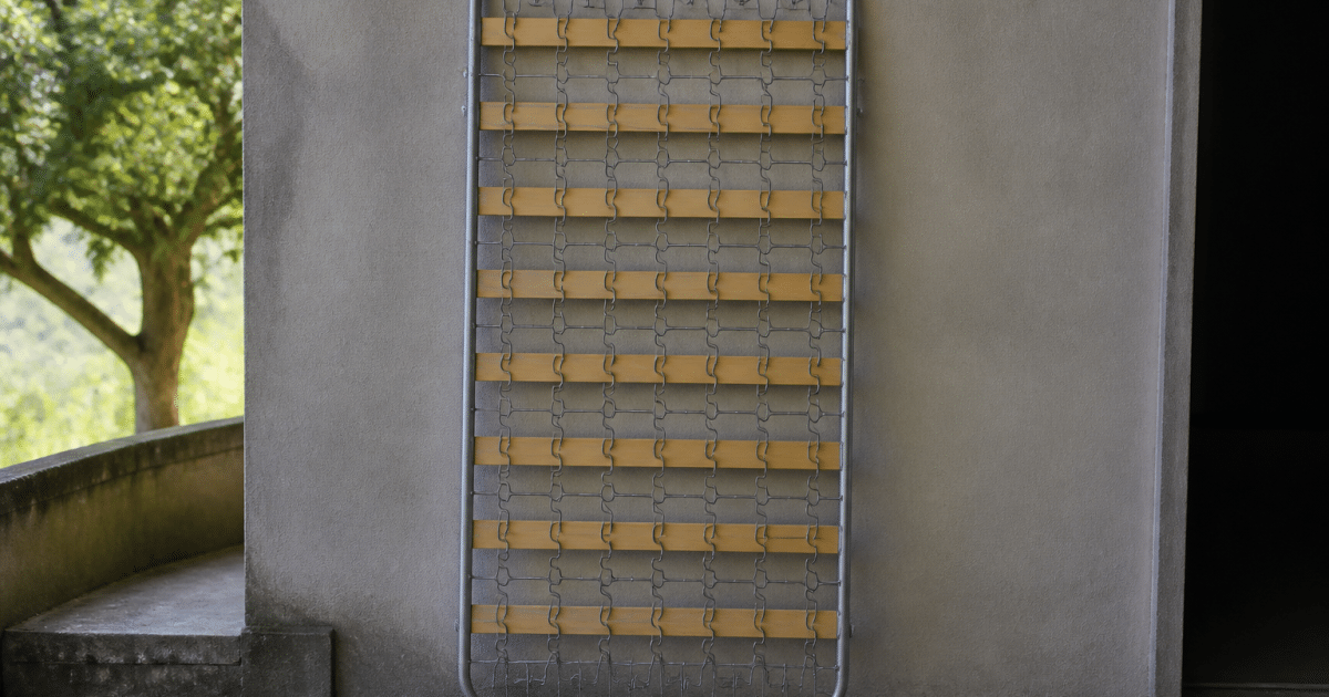 Sommier metallique pose verticalement contre mur gris