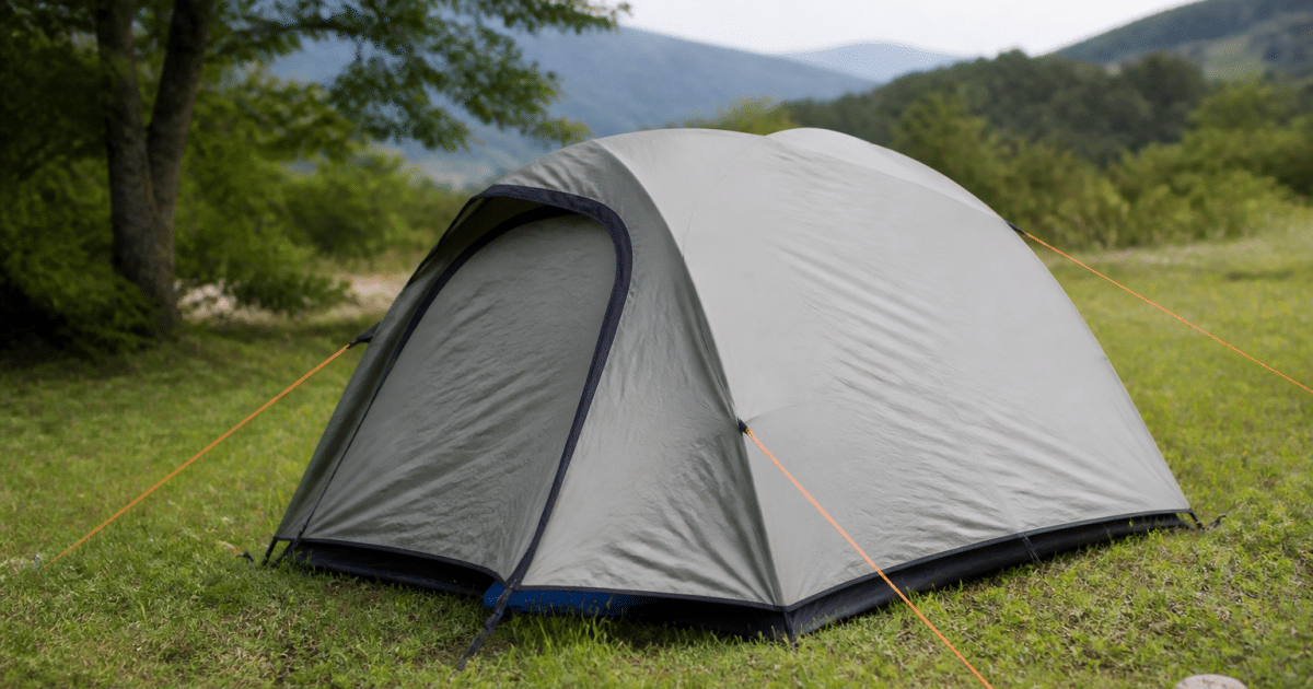 Tente dressée sur terrain herbeux avec piquets enfonces