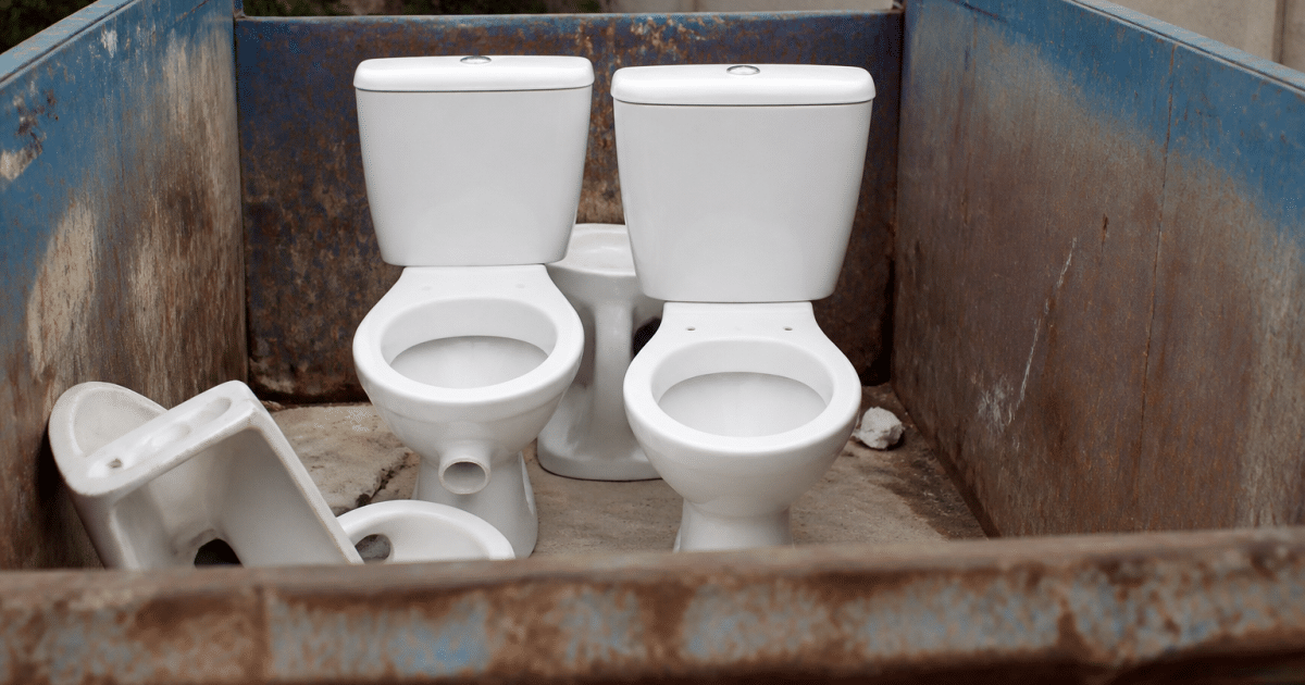 Toilettes blanches posees debout dans benne dechets metal