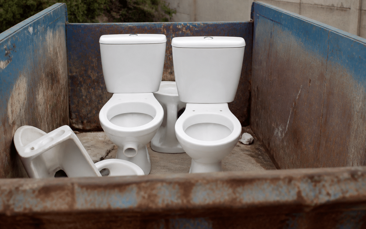 Toilettes blanches posees debout dans benne dechets metal
