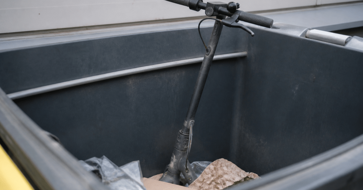 Trottinette electrique posee verticalement dans bac recyclage municipal