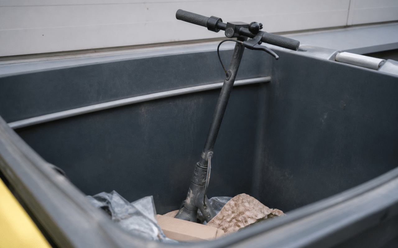 Trottinette electrique posee verticalement dans bac recyclage municipal