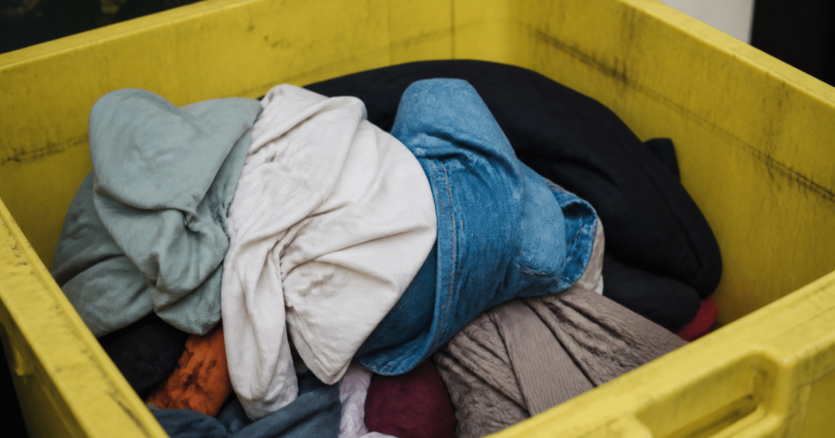 Vetements deposes dans une poubelle de tri selectif jaune