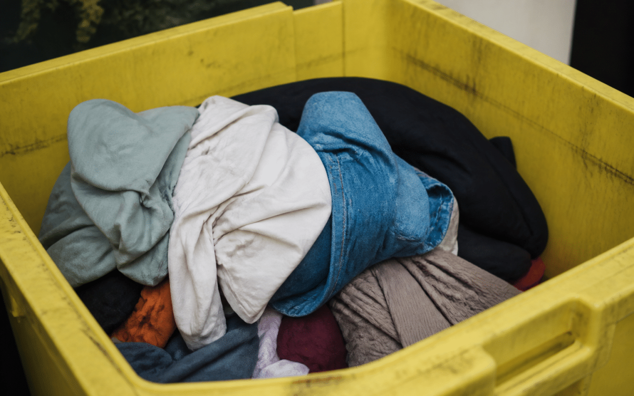 Vetements deposes dans une poubelle de tri selectif jaune