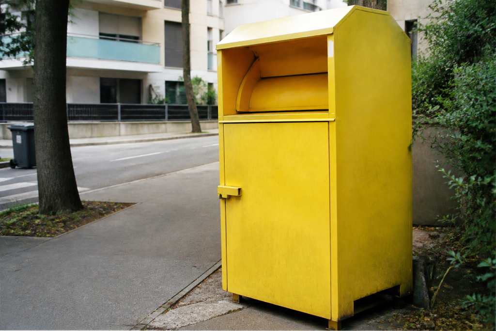 Borne de collecte textile jaune sur un trottoir
