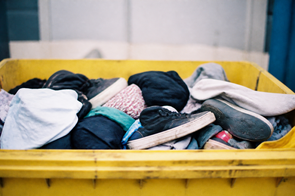 Conteneur jaune rempli de vetements et chaussures usagees