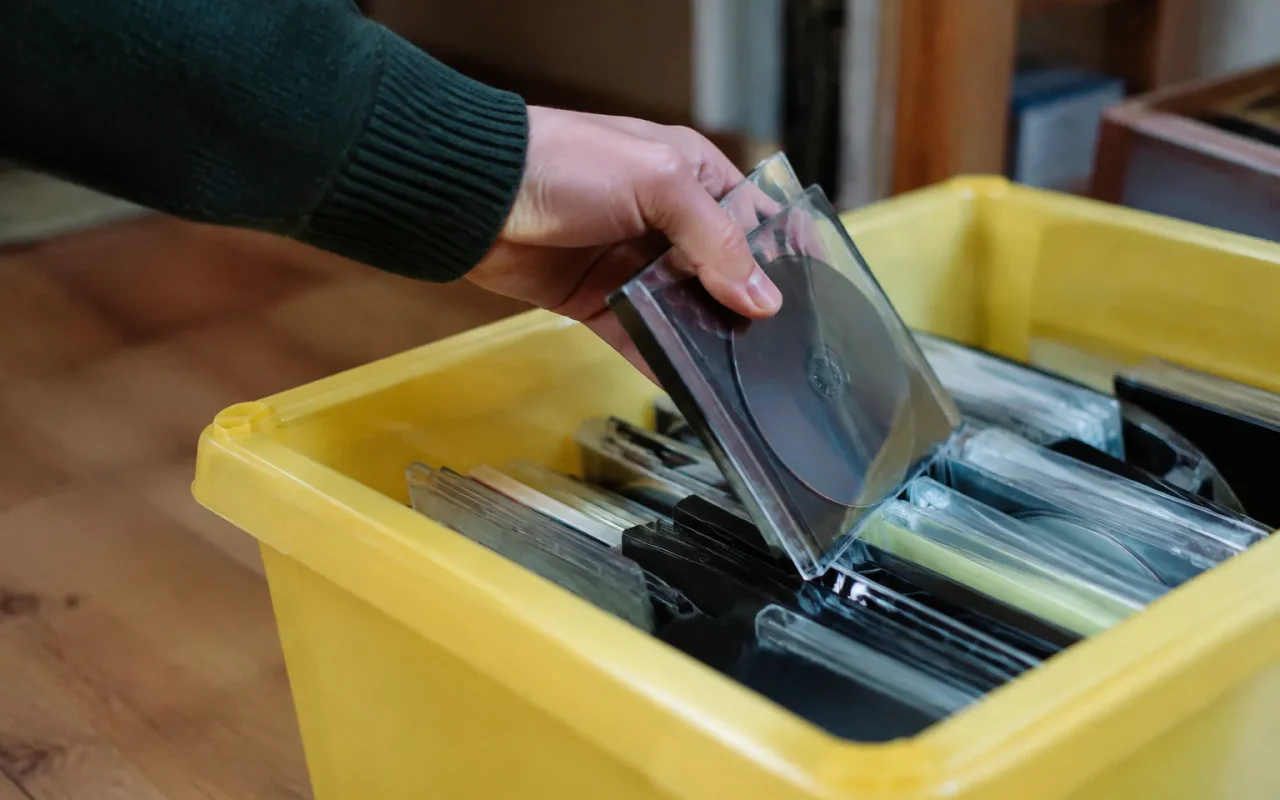 Une main glisse des disques dans un bac jaune