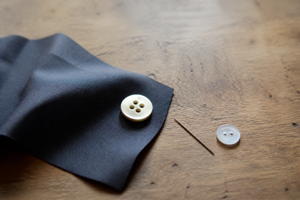 Pull plie, bouton et aiguille sur table en bois